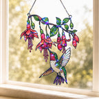 Fuchsia Hummingbird holographic acrylic suncatcher hanging in a sunny window, creating colorful rainbow reflections with a soft garden view in the background.