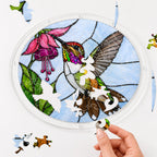 Hand assembling a hummingbird pink fuchsia flower acrylic puzzle suncatcher with colorful puzzle pieces