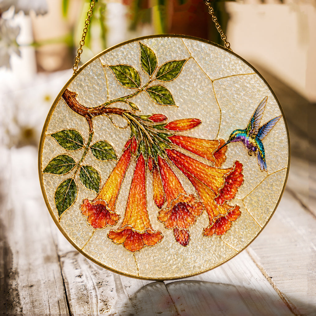 Hummingbird and orange trumpet flower stained glass suncatcher with gold frame on a white background