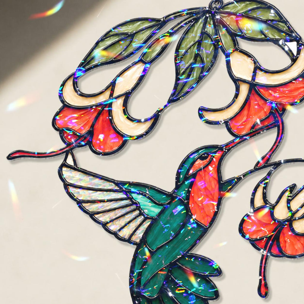 Close-up of hummingbird and fuchsia flower holographic acrylic suncatcher showing broken glass rainbow finish.
