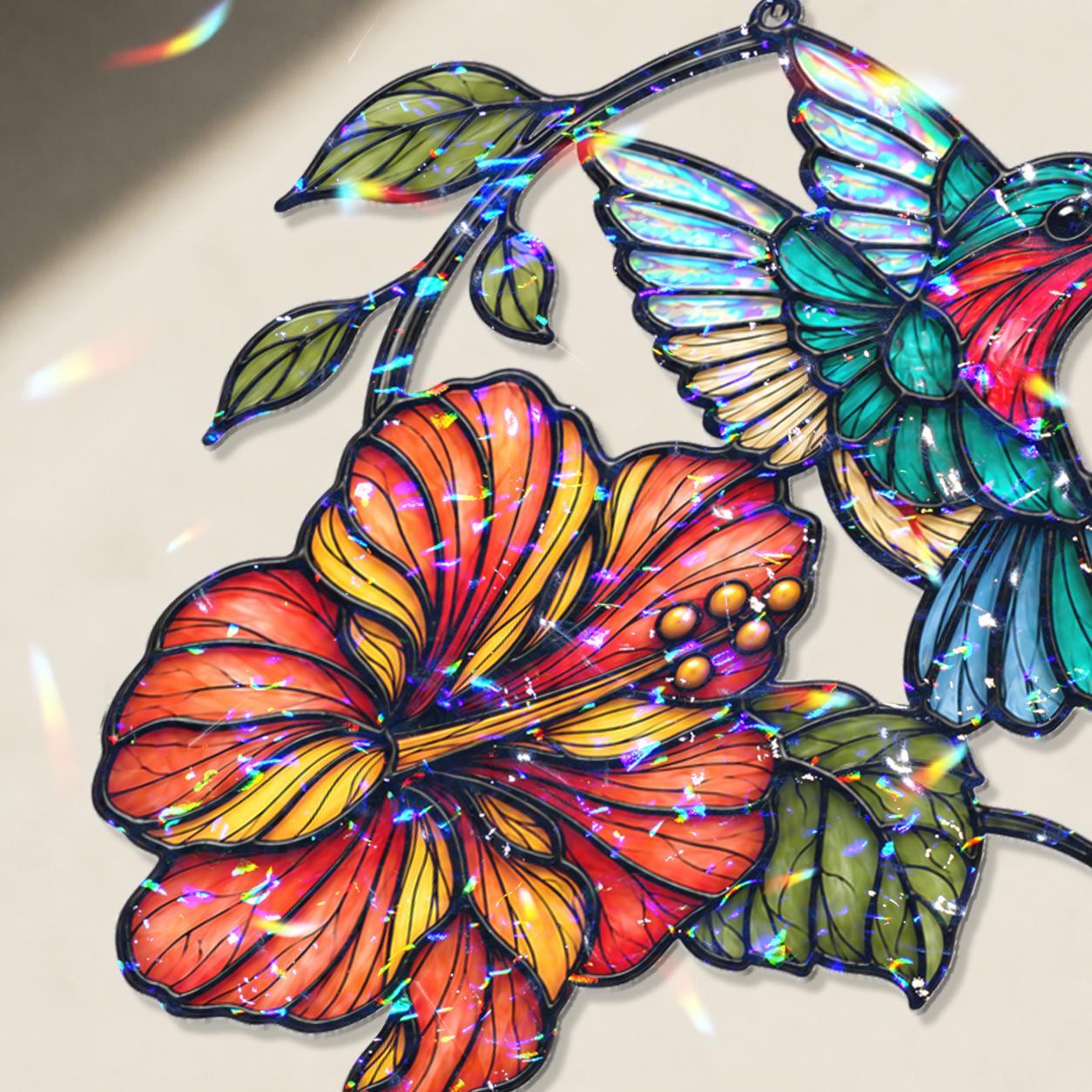 Close-up of hummingbird and orange hibiscus holographic acrylic suncatcher showing broken glass rainbow finish.
