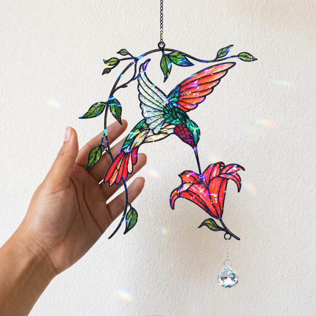 Woman holding a colorful hummingbird holographic acrylic suncatcher with red flower and crystal charm.