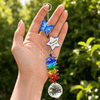 Hand holding personalized memorial butterfly crystal suncatcher outdoors with blue butterfly charm, custom star charm, rainbow crystals, and sparkling crystal ball