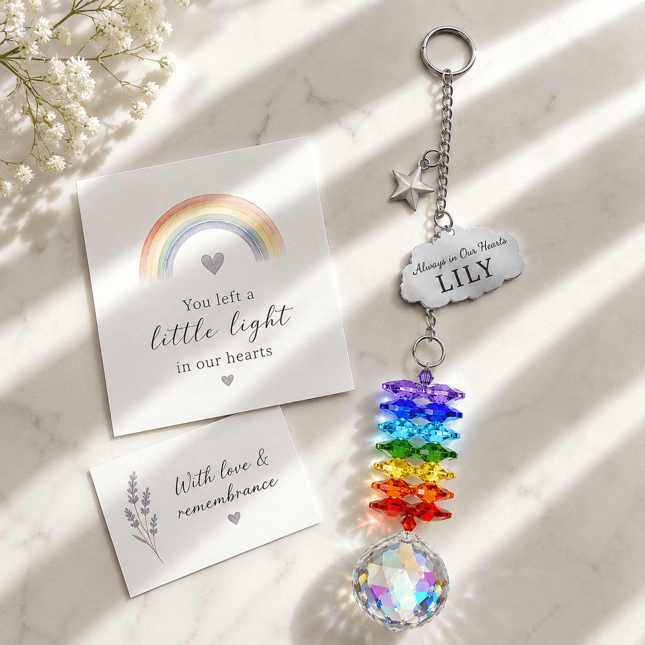 Personalized memorial cloud star crystal suncatcher displayed on marble surface with sympathy card, custom cloud charm, star charm, rainbow crystals, and clear crystal ball