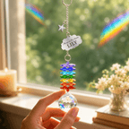 Hand holding personalized memorial cloud star crystal suncatcher by a sunny window with rainbow reflections and custom Lily cloud charm
