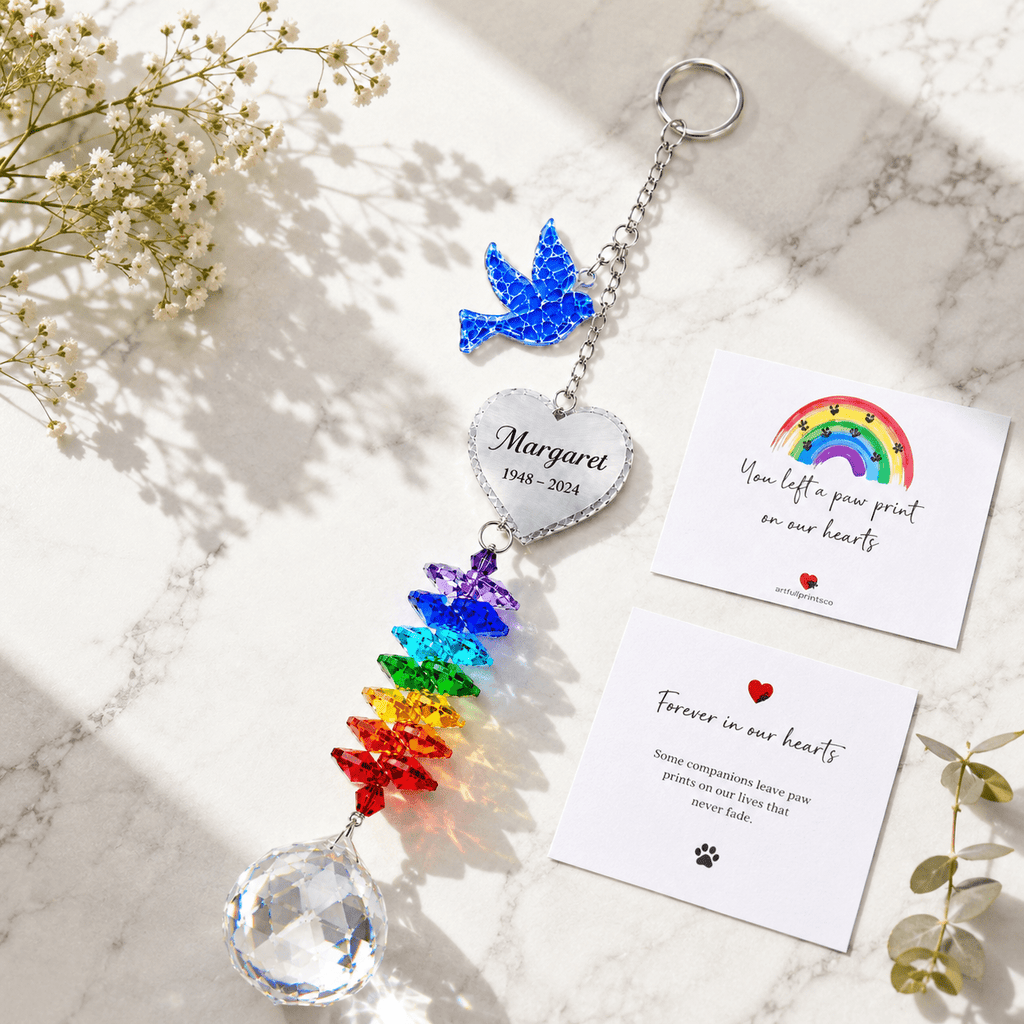 Personalized memorial dove crystal suncatcher displayed on marble surface with sympathy cards, rainbow crystals, and white flowers