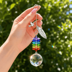 Hand holding personalized memorial feather dove crystal suncatcher outdoors with dove charm, custom feather charm, rainbow crystal strand, and sparkling crystal ball