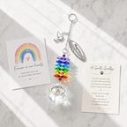 Personalized memorial feather dove crystal suncatcher displayed on marble surface with sympathy cards, rainbow crystals, and soft sunlight