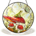 Frog on a red toadstool stained glass suncatcher hanging in a window