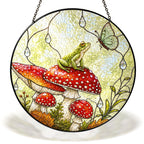 Frog on a red toadstool stained glass suncatcher hanging in a window