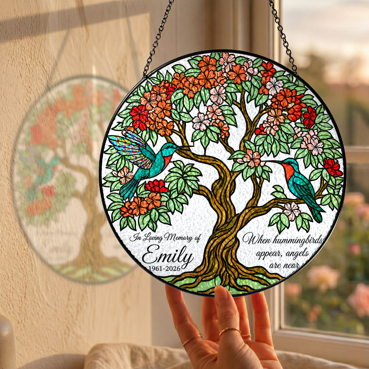 Hummingbird tree of life memorial suncatcher hanging in a sunny window with a garden view