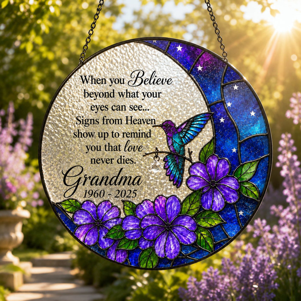 Purple floral hummingbird memorial suncatcher hanging in a garden