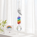 Personalized angel wing memorial crystal suncatcher hanging in front of sheer curtains with remembrance card and white flowers