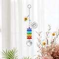 Personalized birth flower crystal suncatcher hanging in front of soft white curtains with marigold heart charm, custom Emma teardrop charm, rainbow crystals, and clear crystal ball
