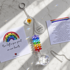 Personalized birth flower crystal suncatcher displayed on marble surface with custom Emma teardrop charm, marigold flower charm, Rainbow Bridge card, and rainbow crystals