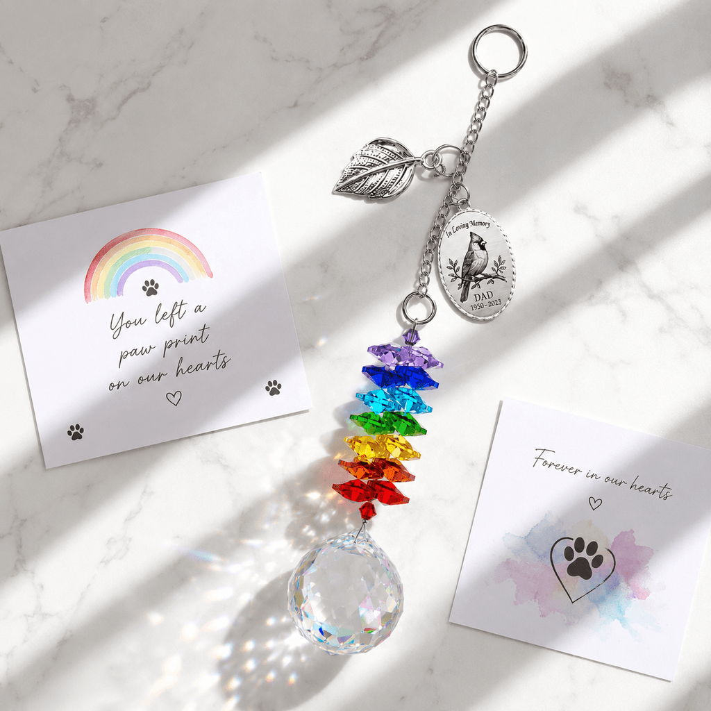 Hand holding personalized cardinal memorial crystal suncatcher outdoors with custom Dad oval charm, silver leaf charm, rainbow crystals, and sparkling crystal ball