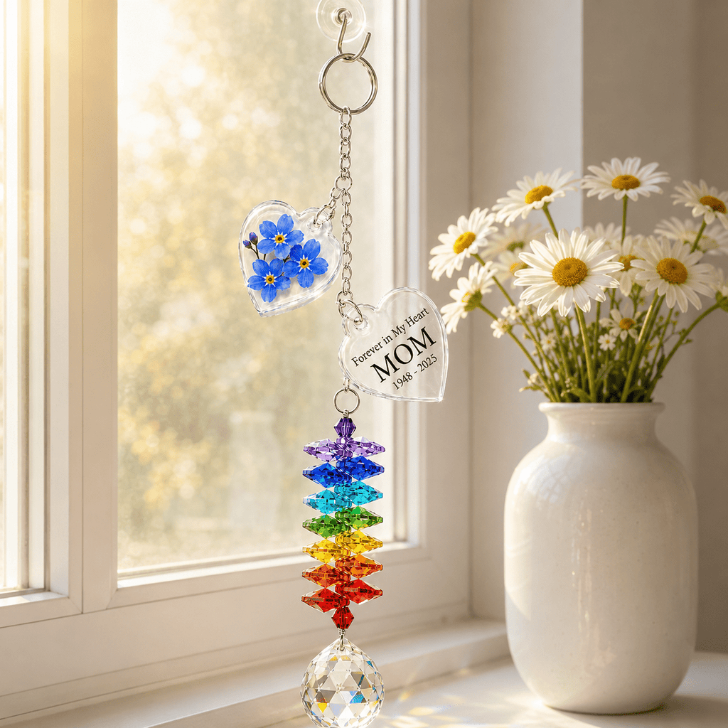 Personalized forget me not memorial crystal suncatcher hanging by a sunny window with blue flower charm, custom MOM star charm, rainbow crystals, and clear crystal ball