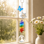 Personalized butterfly memorial crystal suncatcher hanging in front of sheer curtains with Rainbow Bridge sympathy card and white flowers