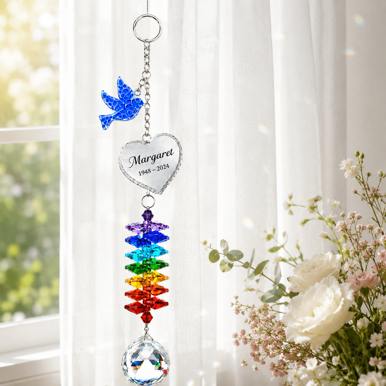 Personalized memorial dove crystal suncatcher hanging by a bright window with custom Margaret heart charm, rainbow crystals, and clear crystal ball