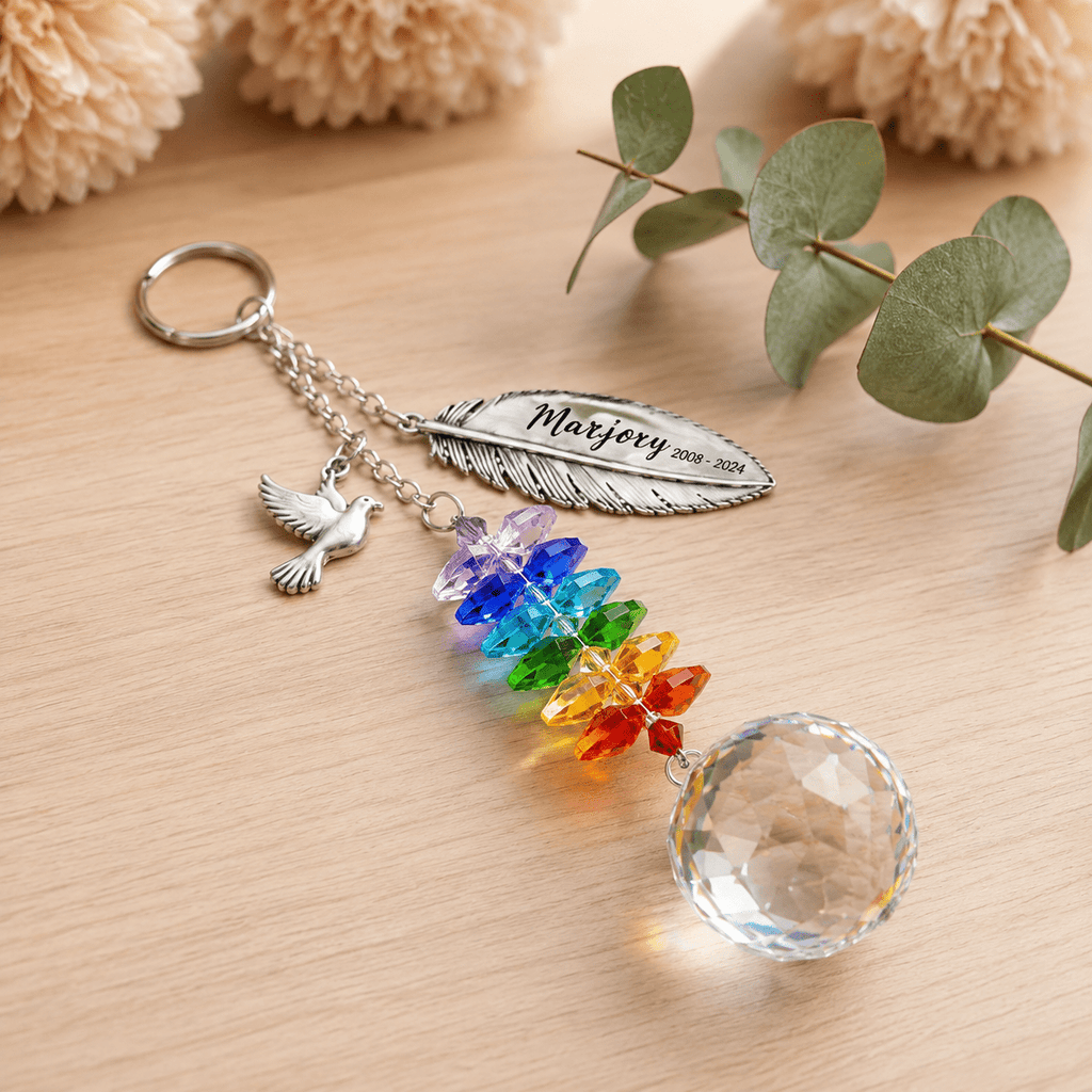 Personalized memorial feather dove crystal suncatcher displayed on wooden tabletop with custom feather charm, dove charm, rainbow crystals, and clear crystal ball