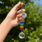 Hand holding personalized Tree of Life memorial crystal suncatcher outdoors with custom Grandma round charm, leaf charm, rainbow crystals, and sparkling crystal ball