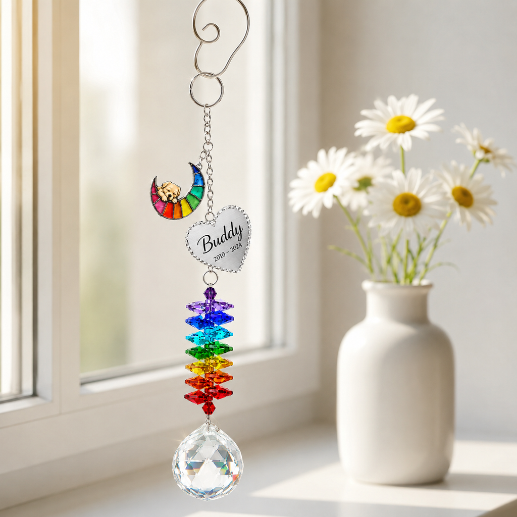 Personalized pet memorial Rainbow Bridge crystal suncatcher hanging from a window hook beside white daisies
