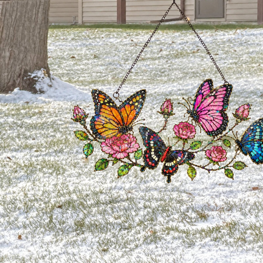 Butterfly Garden & Roses suncatcher in a window over a snowy yard