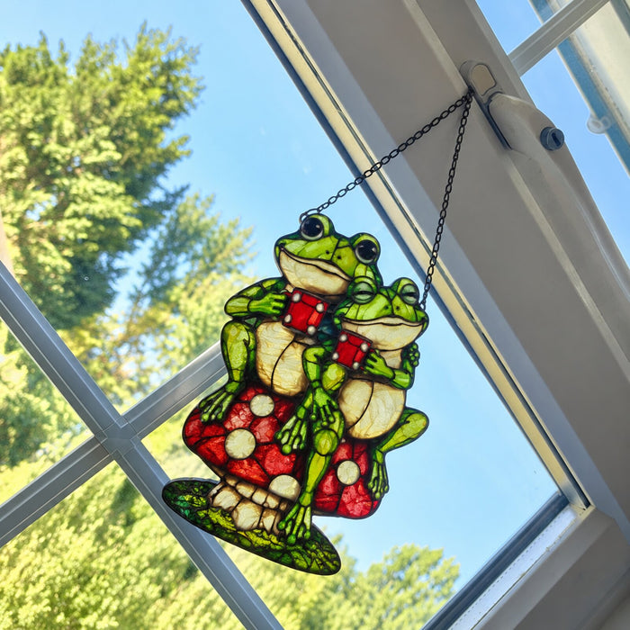 Frog Couple on Mushroom suncatcher in a window against blue sky