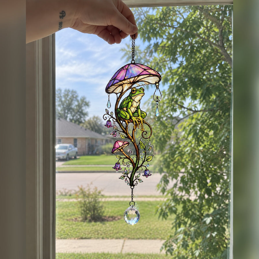 Frog & Mushroom Umbrella suncatcher held up in a bright window