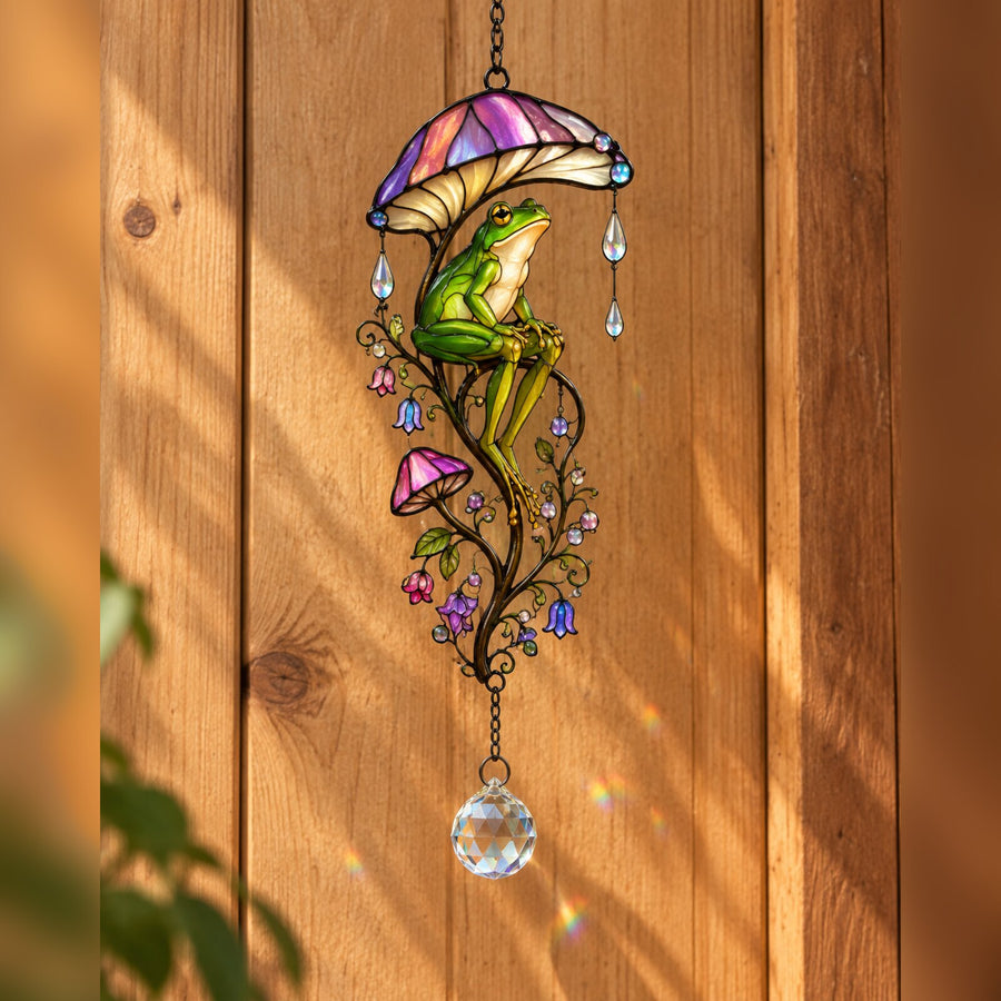 Frog & Mushroom Umbrella suncatcher on a wooden wall in sunlight