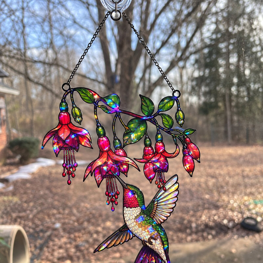 Fuchsia Hummingbird suncatcher in a window facing autumn woods