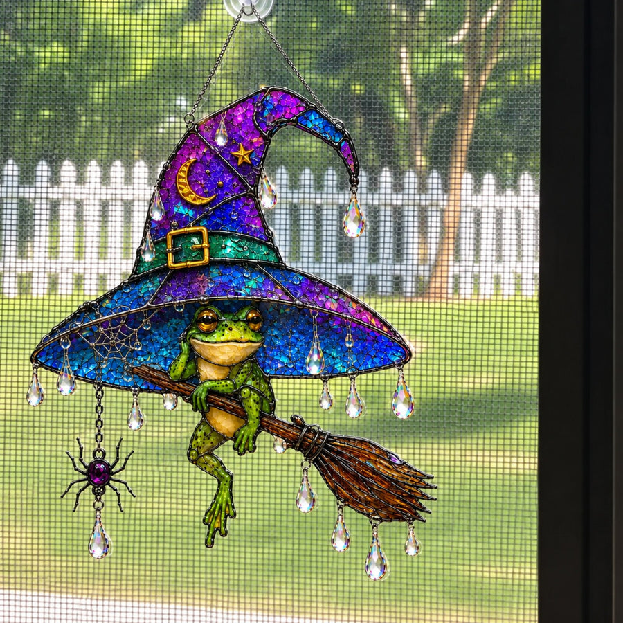 Witch Hat Frog & Broomstick suncatcher on a screen window with picket fence