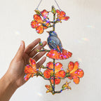 Robin and orange trumpet flower acrylic suncatcher hanging in a sunlit window as home decor