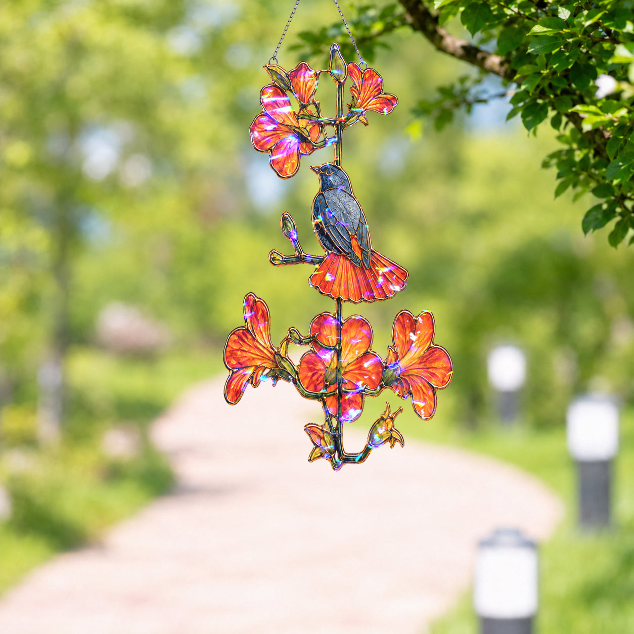 Robin and orange trumpet flower holographic suncatcher catching sunlight and casting rainbow reflections in a window