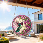 Round pink floral hummingbird acrylic puzzle suncatcher hanging beside a bright balcony window.