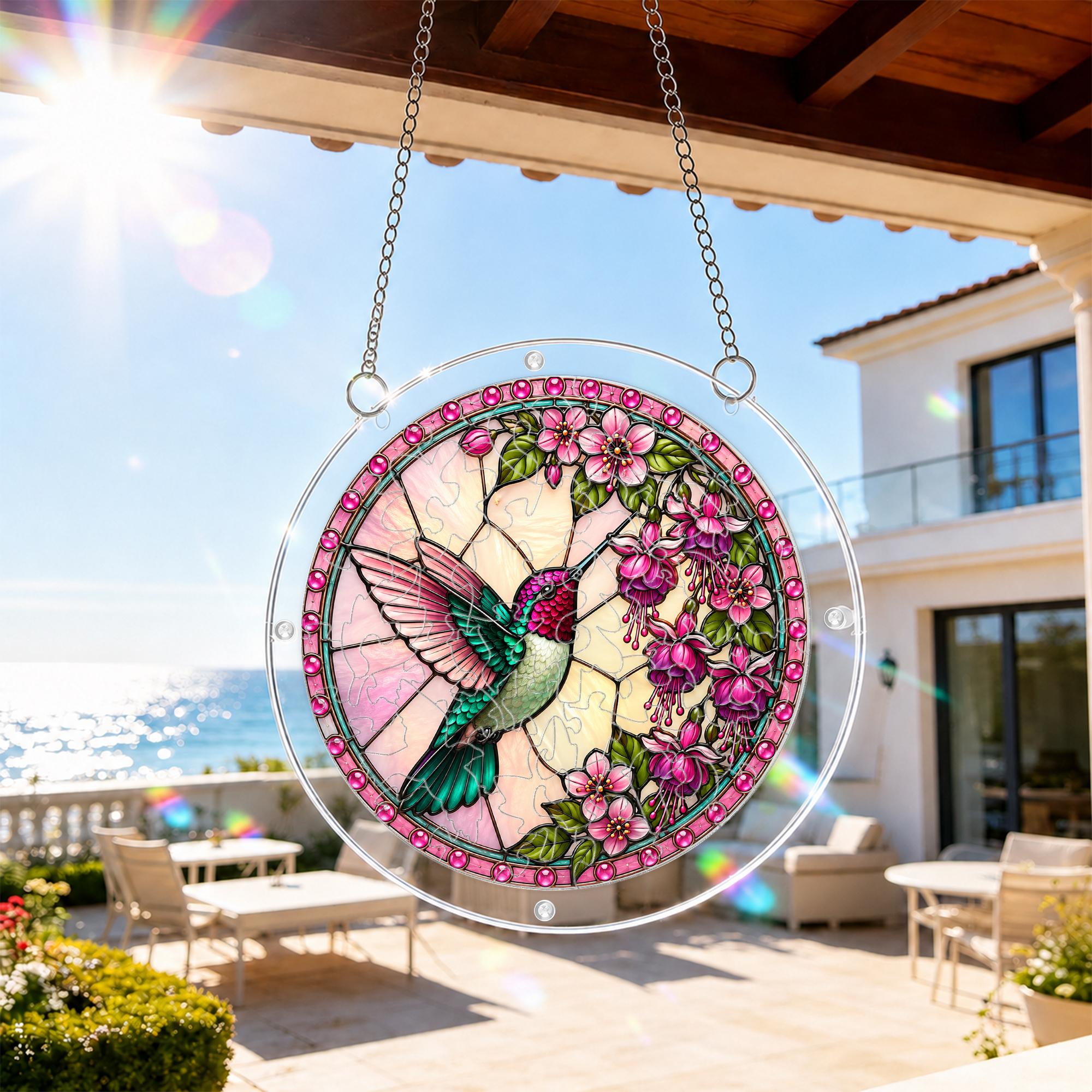 Round pink floral hummingbird acrylic puzzle suncatcher hanging beside a bright balcony window.
