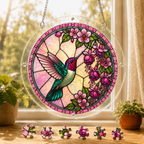 Round Roseglow Hummingbird Garden acrylic puzzle suncatcher hanging in a sunny window with colorful loose puzzle pieces below.