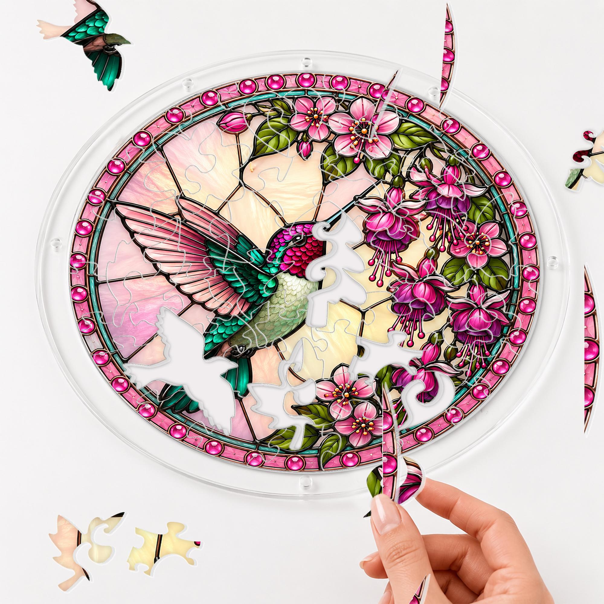 Hand placing a puzzle piece into the Roseglow Hummingbird Garden acrylic puzzle suncatcher.