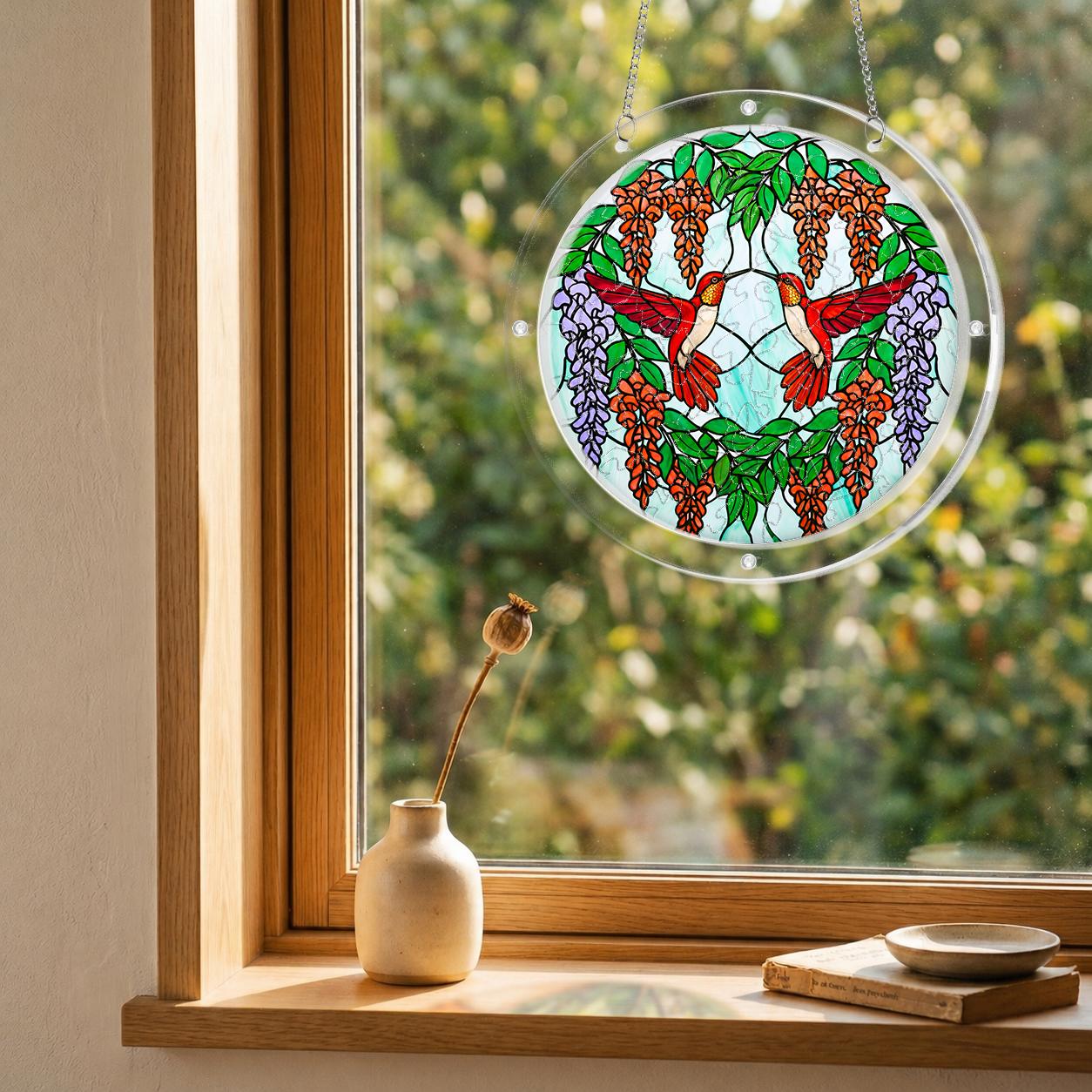 Round scarlet hummingbird acrylic puzzle suncatcher hanging in a cozy wooden window corner with soft natural light.