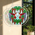 Round acrylic hummingbird puzzle suncatcher hanging on a window with two scarlet hummingbirds, orange blossoms, and purple floral accents.