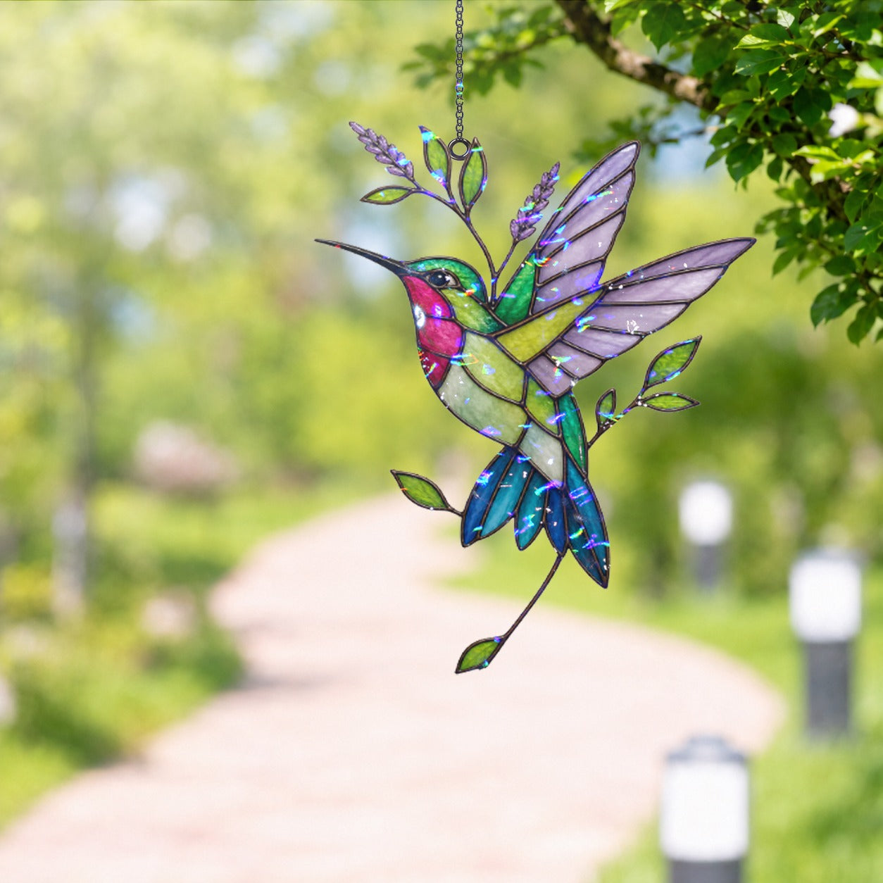 Stained glass style suncatcher with a hummingbird beside a lavender sprig, hanging in a sunlit window with rainbow light
