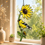 Stained glass style suncatcher with an American goldfinch on a sunflower stem, hanging in a sunlit window with rainbow light