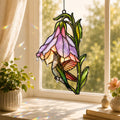 Stained glass style suncatcher with a hummingbird inside a purple foxglove bell flower, hanging in a sunlit window with rainbow light