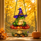 Witch Hat Frog on Red Mushroom suncatcher on its metal hanging chain in a bright window