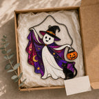 Trick-or-Treat Ghost with Pumpkin Bucket suncatcher displayed in a home window