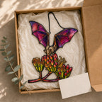 Pink Bat over Autumn Blooms holographic acrylic suncatcher in natural daylight