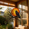 Raven on Branch with Harvest Moon window suncatcher seen against a sunlit garden