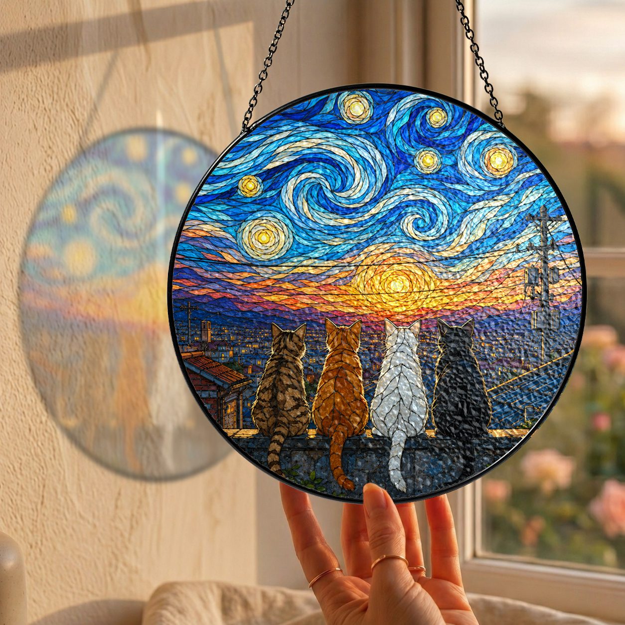 Hand holding the four cats suncatcher at a window