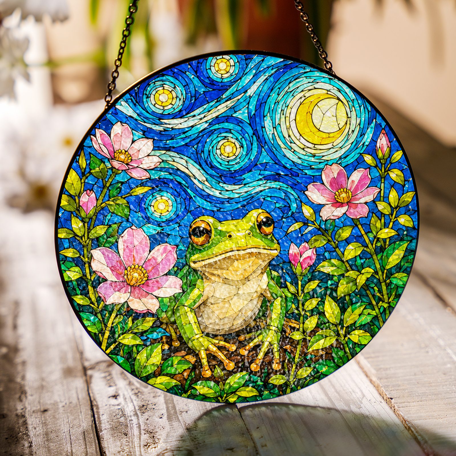 Frog with pink blossoms suncatcher on a wooden table in sunlight