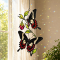 Black swallowtail butterflies and red fuchsia holographic acrylic suncatcher in a sunlit window